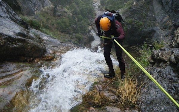Un hombre desciende por una cascada colgado de un cable de seguridad