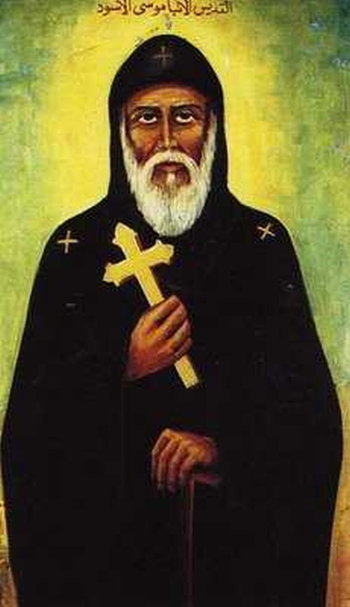 San Moisés el Negro mirando al frente sosteniendo una cruz y tiene un habito  con capaucha