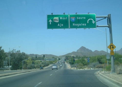 Vemos una carretera y un señal de transito que muestra con flechas los lugares a llegar nogales al sur y ajo al oeste