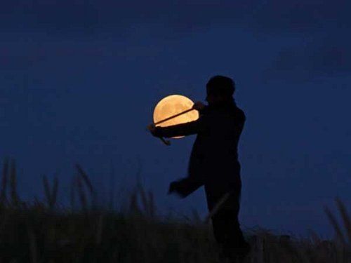 En la noche un hombre toma una cinta  y  parece que partiera la luna en partes iguales