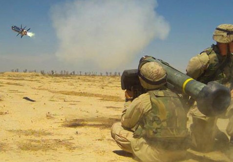Observamos a unos soldados  en el desierto sentados en el piso derriban un helicóptero enemigo