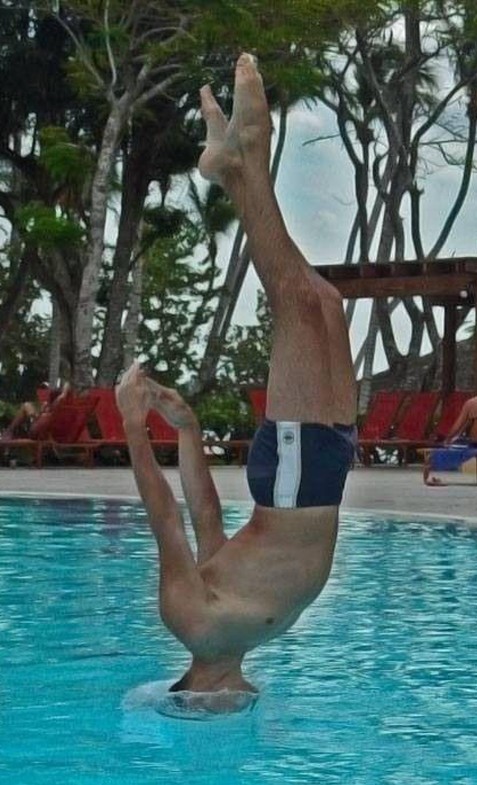 Un hombre clava en una piscina y en posicion recta cabeza abajo los brazos atra no deja hundir y se sostiene un momento así 