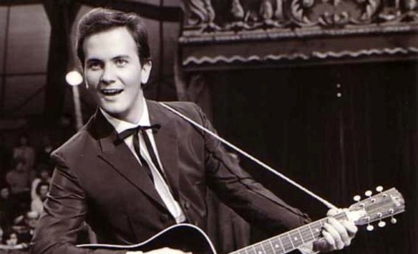 Un joven con una gran sonrisa tocando la guitarra en una presentación