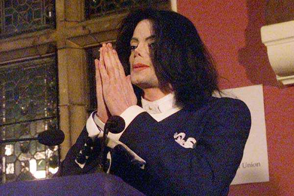 Vemos a un famoso cantante arrodillado con sus manos puestas en actitud de oración