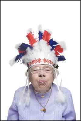 Vemos una abuela sonriendo con un tocado de plumas indigena