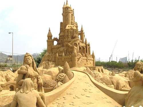Vemos otro hermoso castillo en arena y unas personas cerca de el