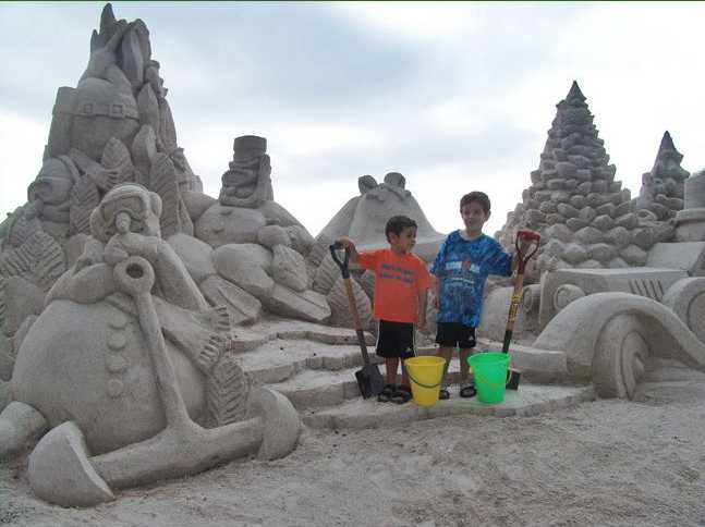 Vemos mas  estatuas hechas en arena aqui vemos a niños mirando las estatuas