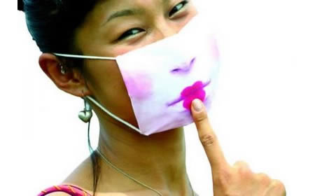 Vemos una mujer de raza asiática que usa un tapa boca  pintado con un lindo corazon en su boca y mejillas sonrosadas