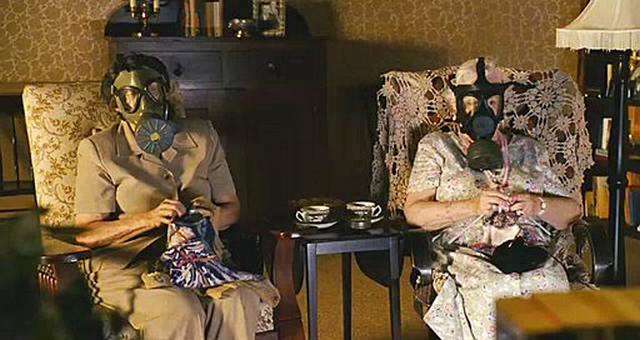 Dos mujeres mayores sentadas cómodamente tejen y llevan mascaras anti-gases  