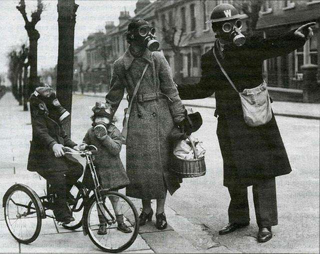 Una señora con dos niños y uno montado en bici hablan con un señor todos  llevan mascaras antigases