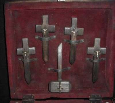 Observamos dentro de la vieja caja donde vemos cuatro cruces con crucifijos tallados y una pequeña daga