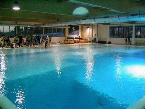 Vemos una piscina con aguas azules profundas en un sitio de club