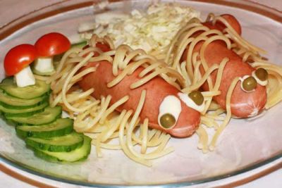 Tenemos aqui dos salchichas medianas  dentro salen espaguetis y como ojos tienen salsa blanca y arvejas y un gusano hecho por pepino cohombro y los ojos dos partes de queso y mitad de tomate