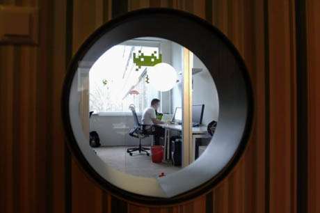 Vemos una ventana redonda por donde se ve a un hombre que trabaja en su escritorio