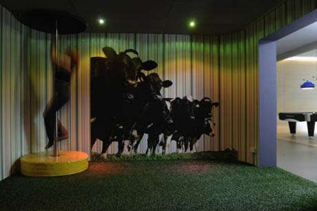 vemos una pequeña estancia donde sobre una pared se ve una pintura de vacas que corren y en un rincon vemos una barra de decenso
