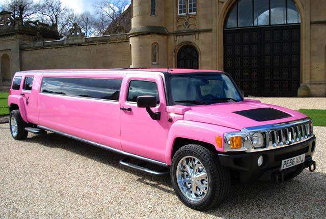 Vemos una limusina en color rosa fucsia  con tre ventanas a cada lado y rines de liujo