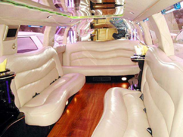 Vemos el interior de una limusina con comodos sofas tapizadpos en blanco y hermosos pisos en parket
