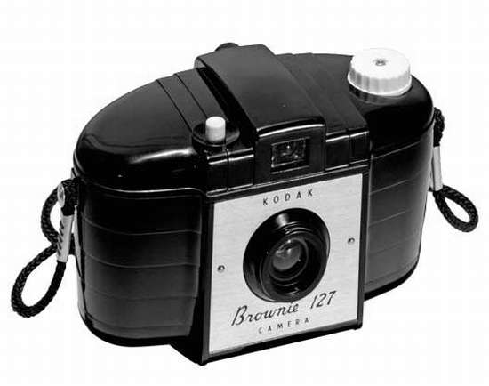 vemos una cámara de fotografía  de un tiempo atras en color negro y una pequeña correa para agarrarla y se ve el botón para obturar y tomar la foto 