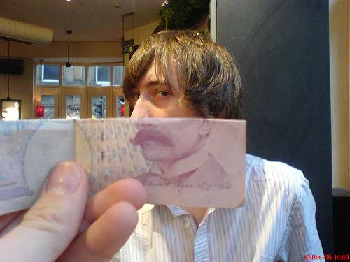 Un rostro de un hombre sobre el cual se coloca un billete  y se iguala con la imagen del billete