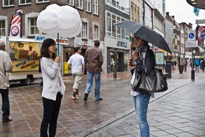 Vemos ados personas en la calle una con sombrilla tradicional y otra con una sombrilla en forma de nube
