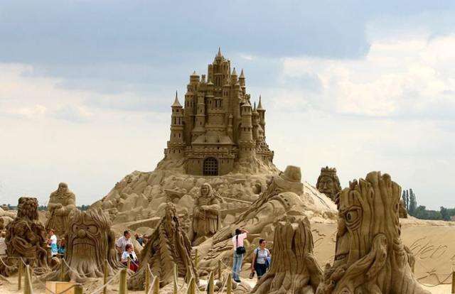 Vemos un castillo en arena  en una colina y abajo alrededor una cantidad de    imagenes d     e