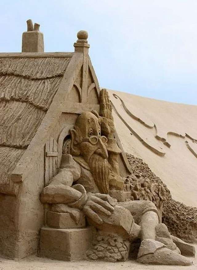 Vemos una hermosa casa hecha  en arena donde un hobre sentado cuida de ella y con su zapato apasta la cara de un rey 