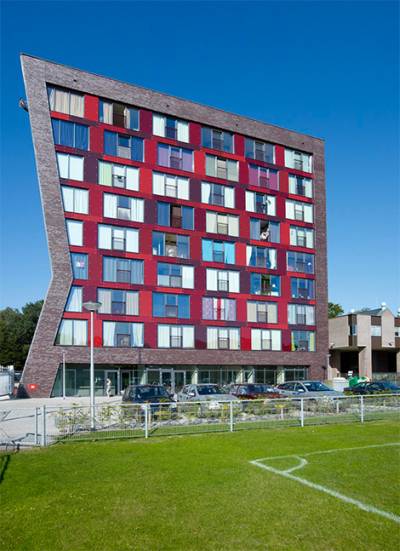 Es muy bonito  este edificio en una forma caprichosa pintado en colores rojos y sus ventanas con los marcos azules