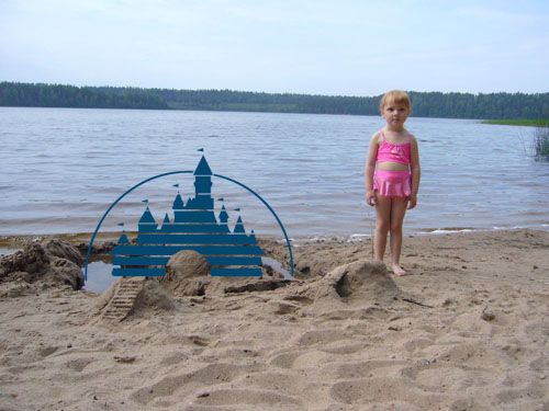 Vemos a una pequeña niña en una playa contraje rosado  al pie de un pequeño castillo azul 