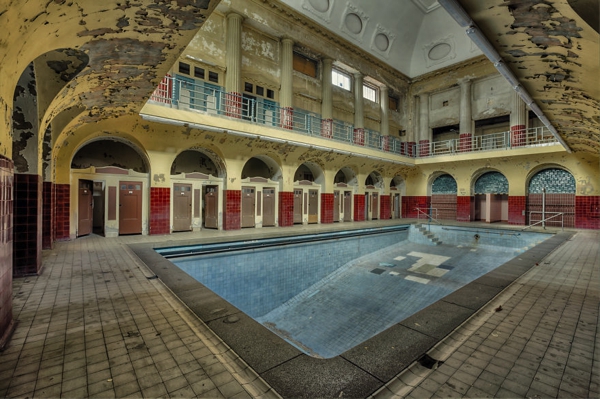 Una piscina en el medio de una propiedad en la cual las paredes estan muy despicadas