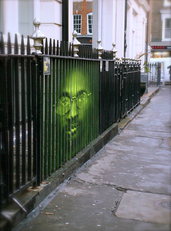 Un hombre dibujado en unas rejas, el hombre esta pintado de color verde y tiene gafas