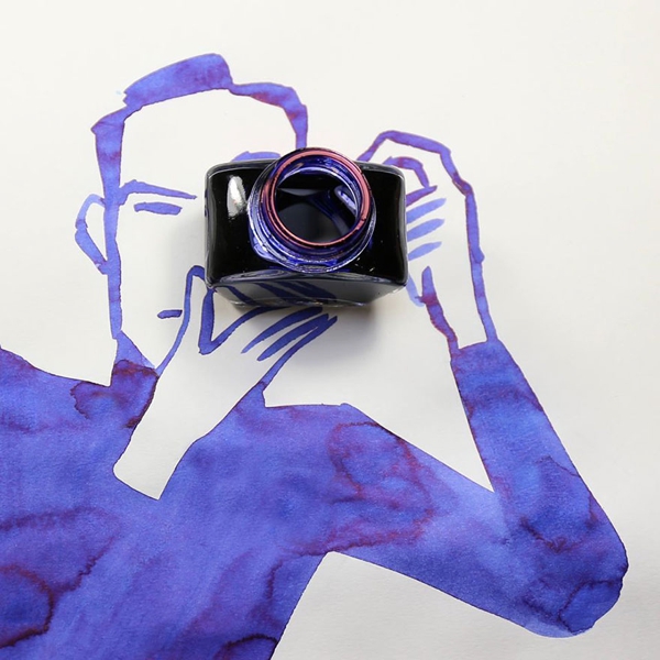 Imagen con un hombre con una cámara fotográfica todo pintado en  color morado