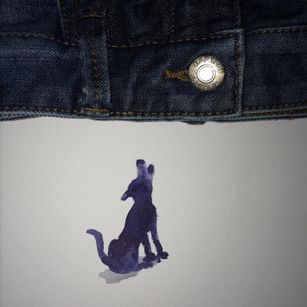 Se observa una parte de la cintura de un jean con botón dorado y un perro que le ladra