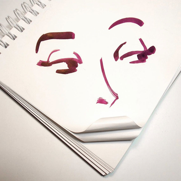 Se observa  un cuaderno con figuras de un rostro en color terracota con posición  en forma de rombo