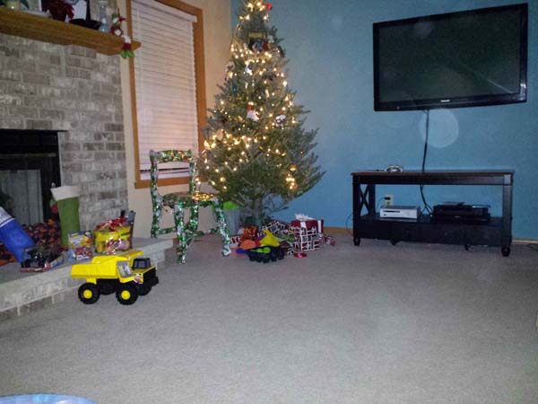 Ahora vemos un salón grande donde esta el árbol de navidad la silla envuelta en papel navidad y hay otros muchos objetos en suelo