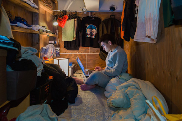 Un hombre navega en su computador en su estrecho cuarto