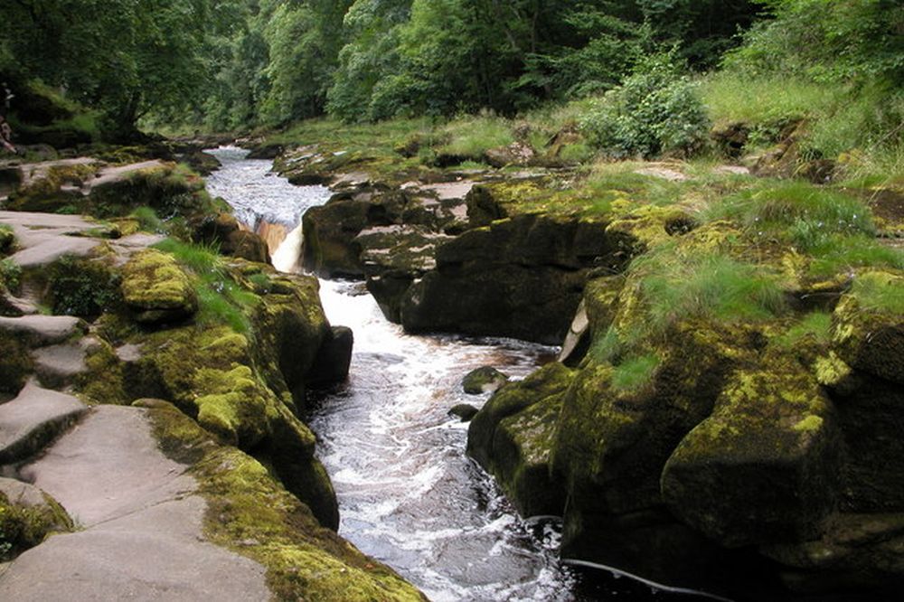 Un río muy angosto con una gran corriente y sobresalen las piedras