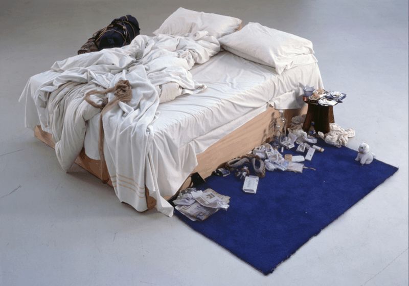 Una cama totalmente desorganizada con articulos tirados en el piso