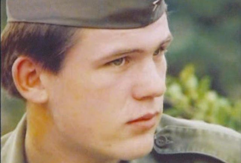 Un joven en vestido militar mira hacia un lado con tan solo su cabeza siendo visible