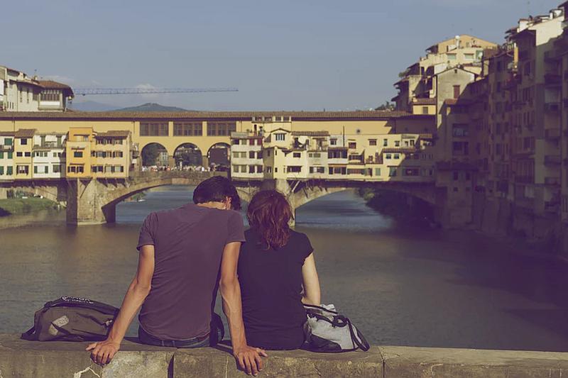 Una pareja que observa una ciudad  un puente y el mar