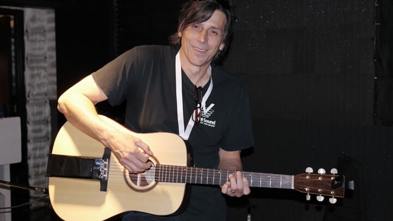Un hombre con una guitarra y una expresión sonriente