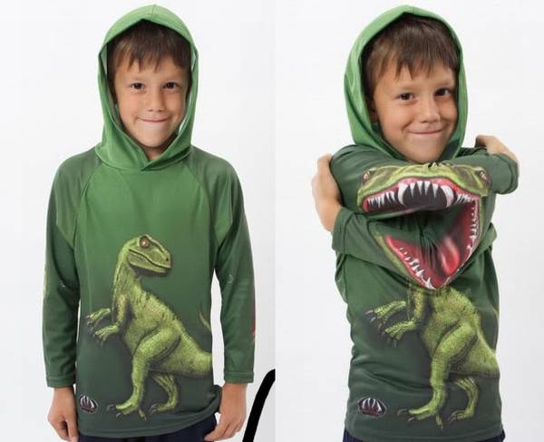 Un par de niños con buzos color verde con un  dinosaurio en un buzo está parado y en el otro buzo aparece en posición de ataque