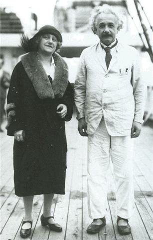 Una mujer con con abrigo y sombrero y un hombre con un traje claro sonrien