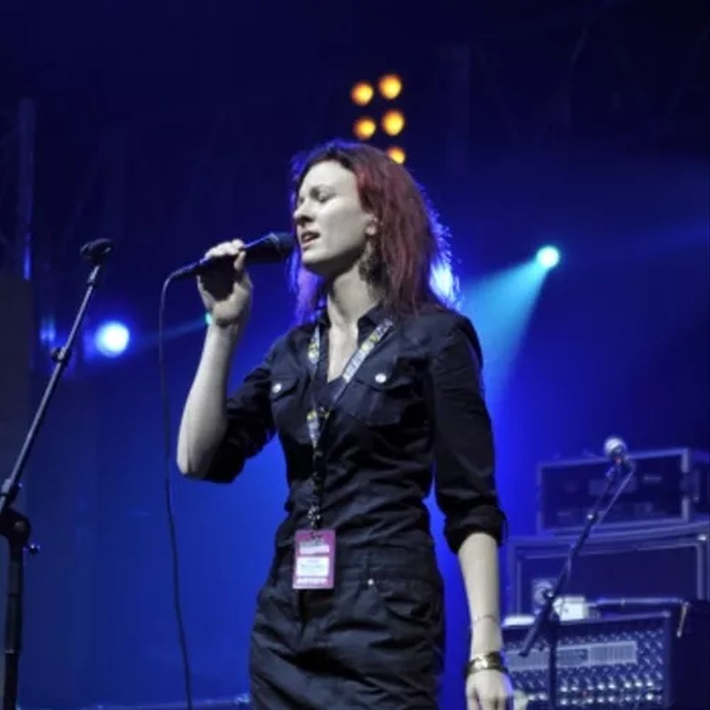 Una mujer vocalista sostiene un micrófono durante un concierto