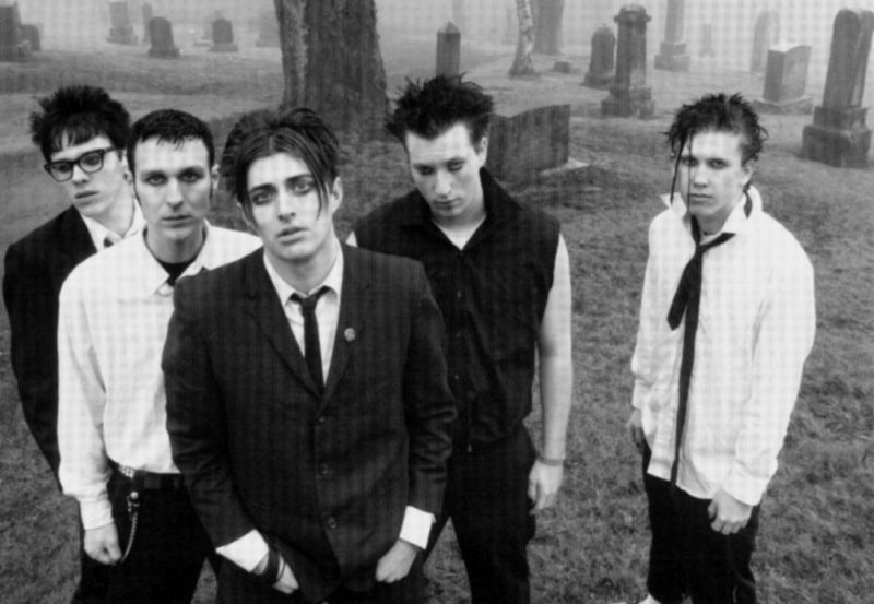 Cinco jóvenes con traje y corbatas en un cementerio