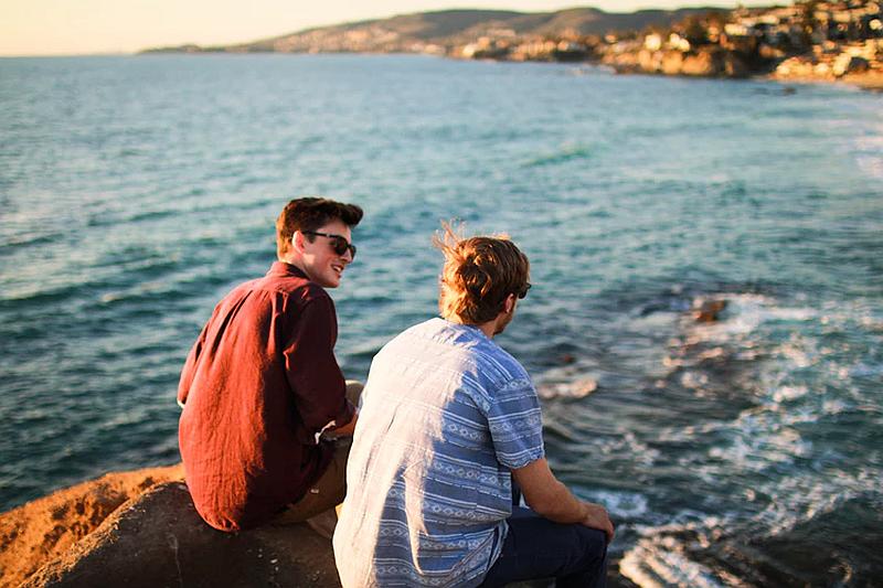Vemos a dos amigos  sentados en parte alta mirando el mar