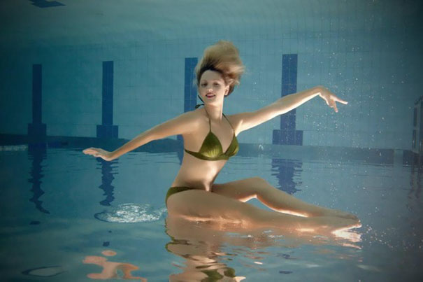 Una mujer sentada en una piscina  sobre el agua haciendo ejercicio