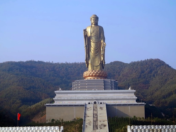 Una estatua dorada de Buda sobre un pedestal y al fondo montañas
