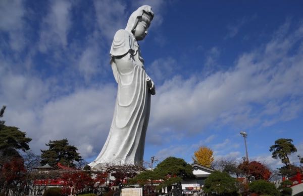 Estatua en color blanco femenina sobre un gran pedestal con rostro inclinado en posición de meditacion 