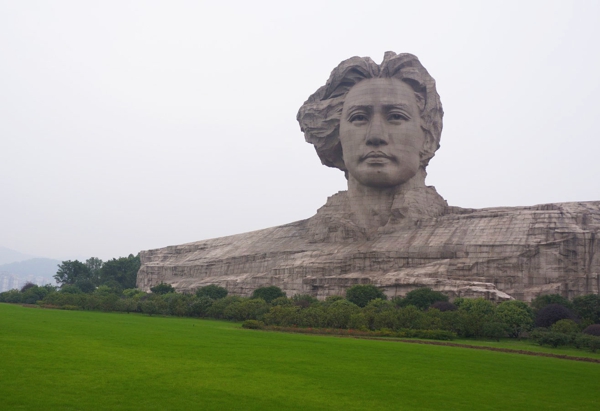 Figura de una gran cabeza gris sobre inmenso pedestal dominando un gran valle