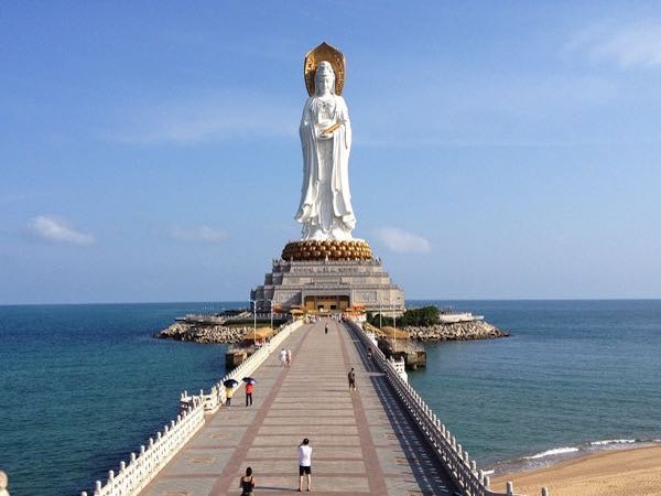 Imagen femenina toda en blanco de una divinidad en un pedestal a la orilla del mar